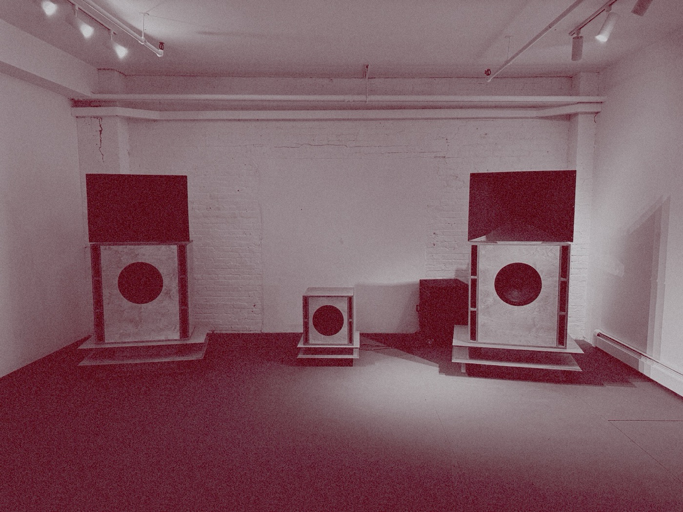 A pair of Prima Stacks in a gallery room with the custom subwoofer between them, duotone pink on silver